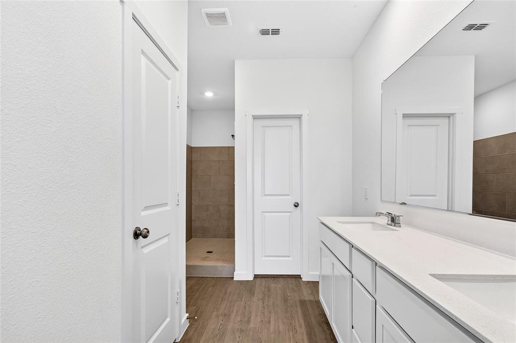 656 Waymaker Way Princeton, TX 75407 - Photo 32 of 40 Dual vanity featuring white cabinetry, integrated sinks, and a large wall-mounted mirror