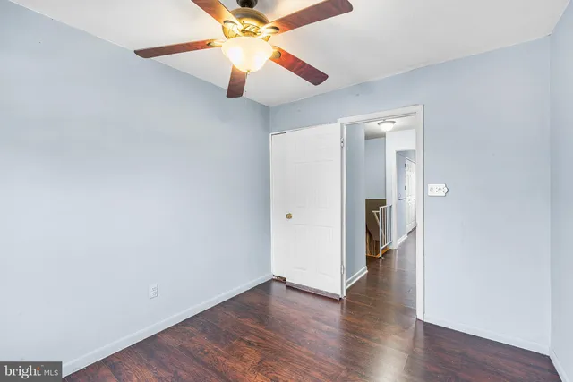 an empty room with wooden floor and a ceiling fan