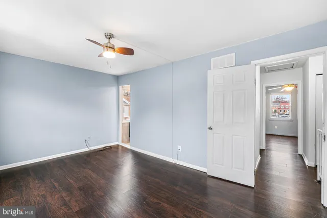 an empty room with wooden floor and ceiling fan