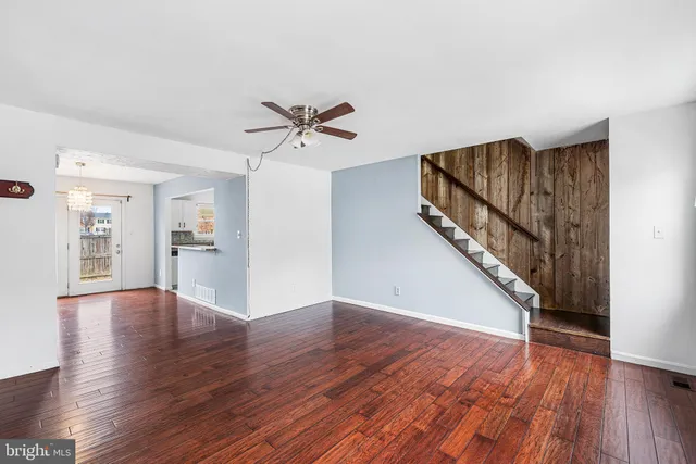 a view of an empty room with wooden floor and a kitchen