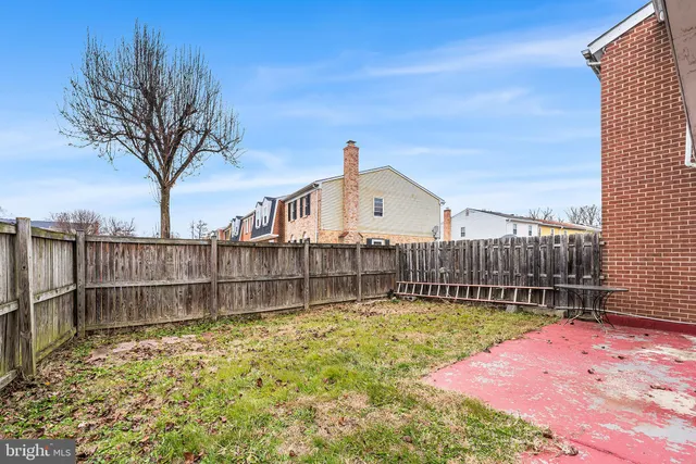a view of a backyard with a large tree and wooden fence