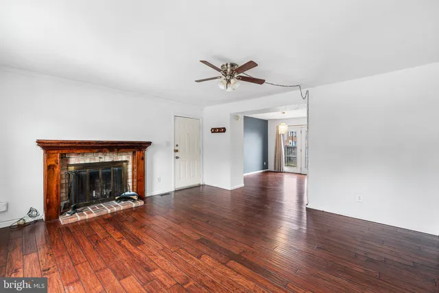 a view of an empty room with wooden floor fireplace and a window