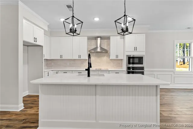 a view of a kitchen with stainless steel appliances granite countertop a sink a stove a refrigerator and white cabinets