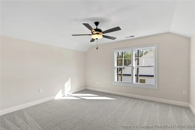 an empty room with chandelier fan and windows