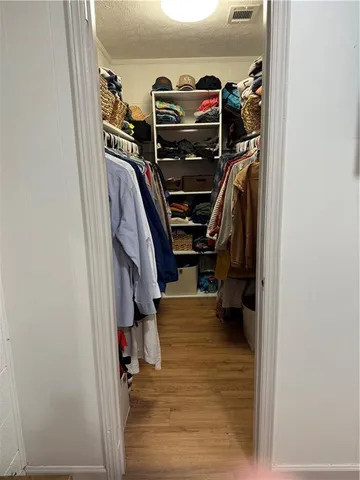 a view of walk in closet with clothes and shoes