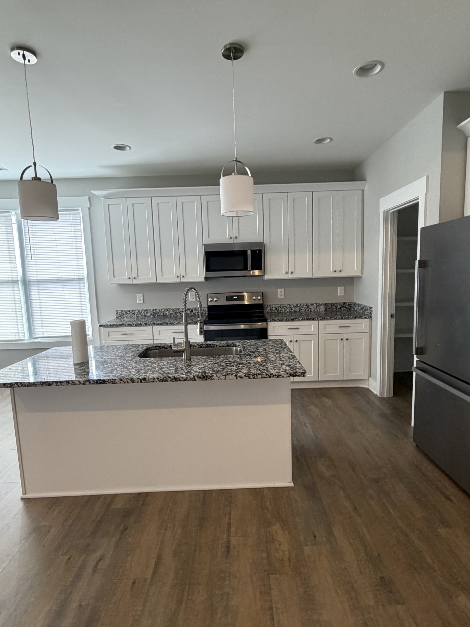 442 Bill Fuson Road McMinnville, TN 37110 - Photo 13 of 29 a large kitchen with granite countertop a stove a sink dishwasher a refrigerator and white cabinets with wooden floor