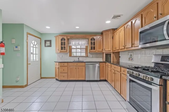 a kitchen with stainless steel appliances granite countertop a stove a sink and a microwave