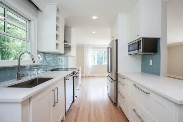 a kitchen with granite countertop a sink a counter space appliances and cabinets