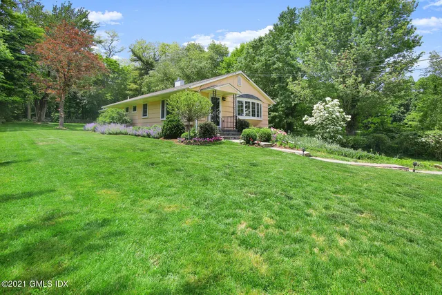 a aerial view of a house next to a yard with potted plants and large trees