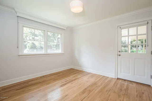 a view of an empty room with wooden floor and a window