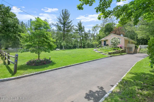 a view of a house with a yard and large trees