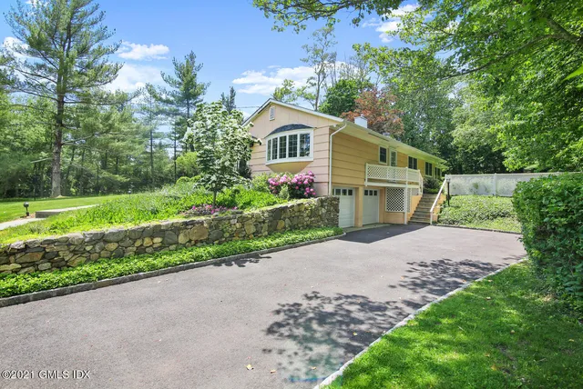 a front view of a house with a garden and trees