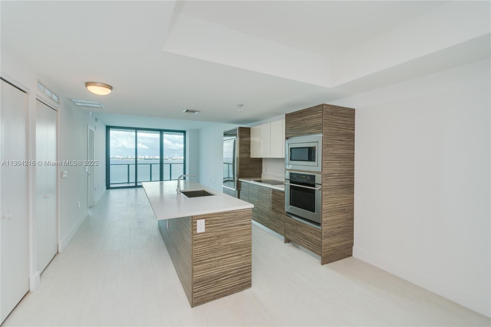 a living room with stainless steel appliances kitchen island a large window and kitchen view