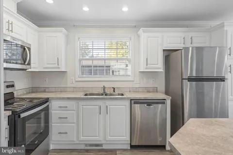 a kitchen with granite countertop a sink stove and refrigerator