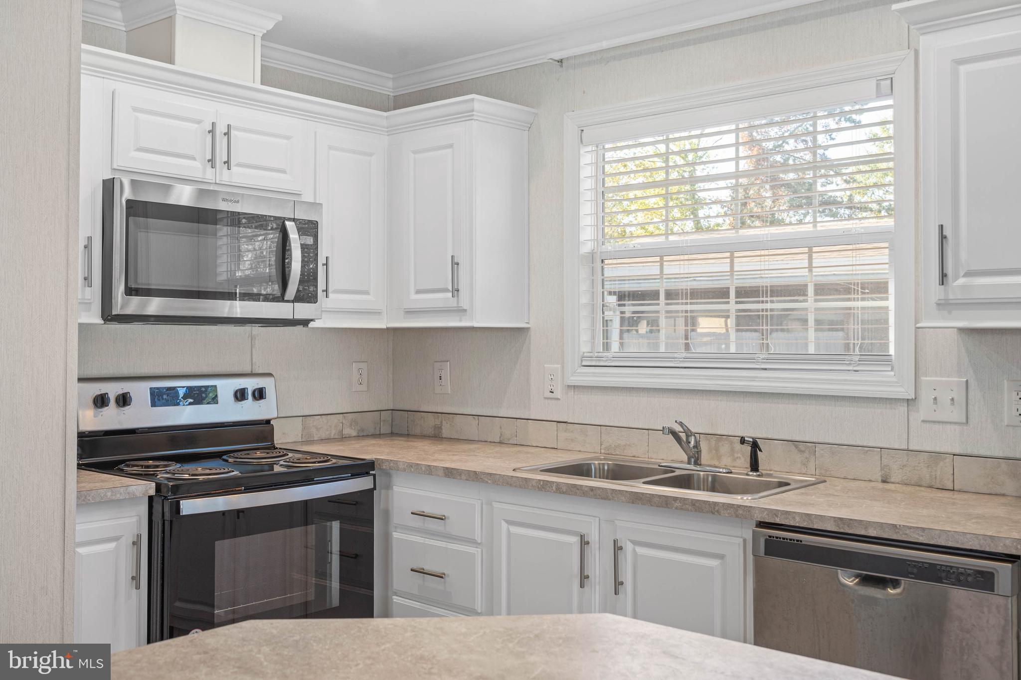 17247 Pine Water Drive Lewes, DE 19958 - Photo 3 of 32 a kitchen with stainless steel appliances granite countertop a sink stove and microwave