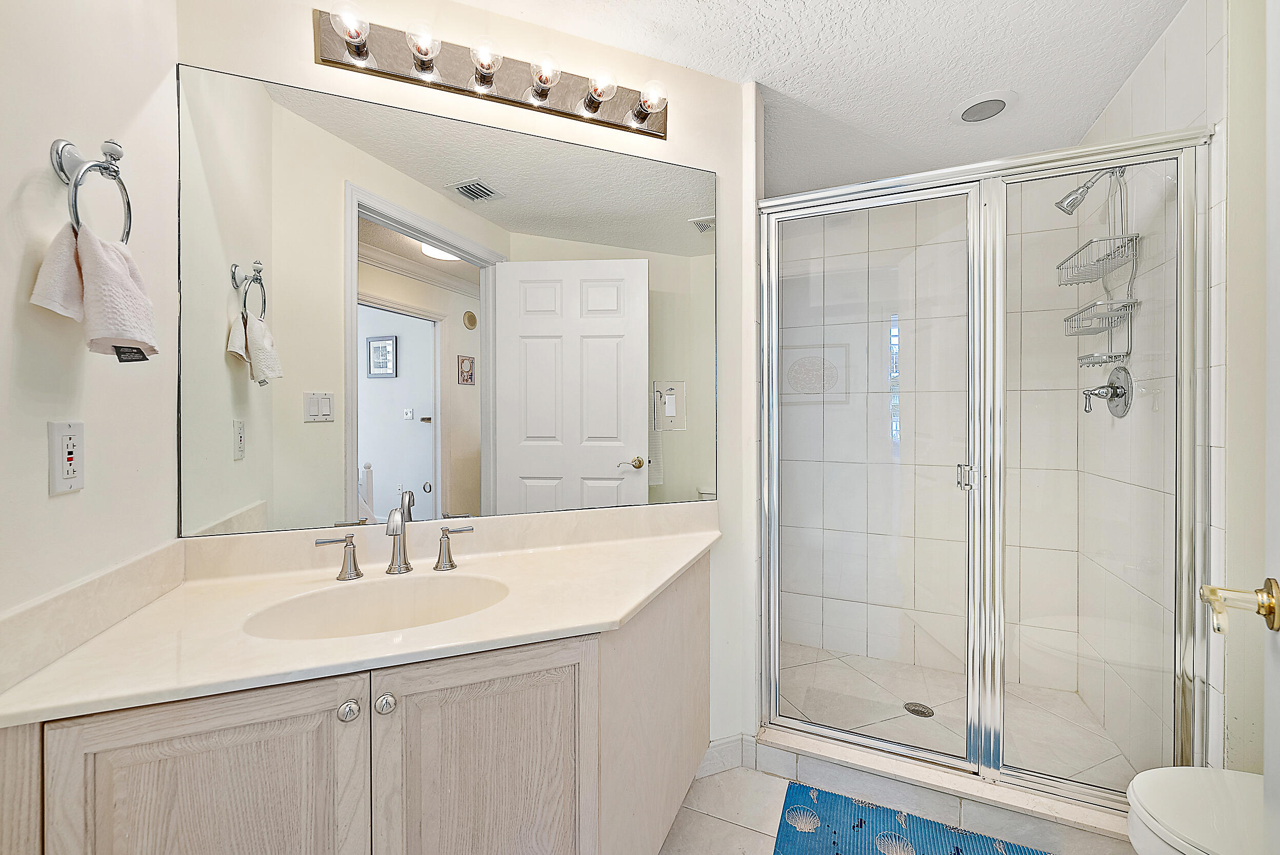 221 Ocean Grande Boulevard, Unit 407 Jupiter, FL 33477 - Photo 20 of 39 a bathroom with a shower sink and mirror