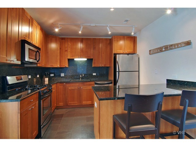 657 West Fulton Street, Unit 501 Chicago, IL 60661 - Photo 4 of 11 a kitchen with stainless steel appliances granite countertop a refrigerator a stove and a sink