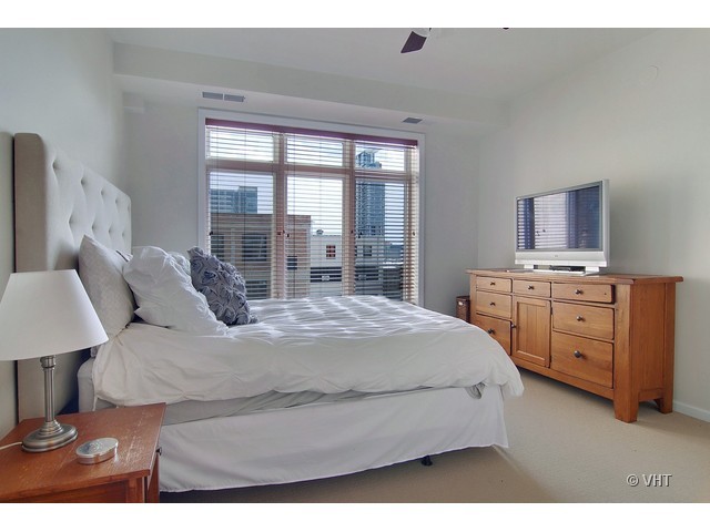 657 West Fulton Street, Unit 501 Chicago, IL 60661 - Photo 9 of 11 a bedroom with a bed a dresser and a large mirror