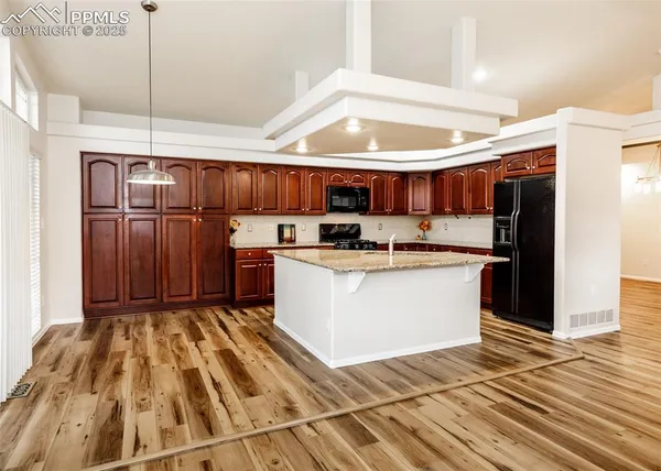 a kitchen with kitchen island a stove a refrigerator and a sink with wooden floor