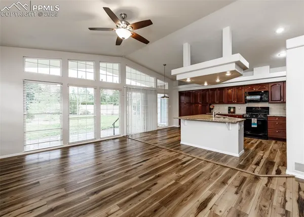 a large kitchen with stainless steel appliances kitchen island a large counter top and a wooden floors
