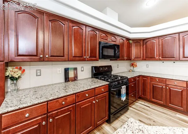 a kitchen with stainless steel appliances granite countertop wooden cabinets a stove top oven a sink and dishwasher