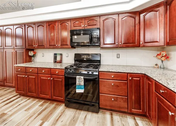 a kitchen with stainless steel appliances granite countertop wooden cabinets stove top oven and sink