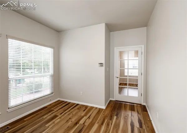 a view of an empty room with a window and wooden floor