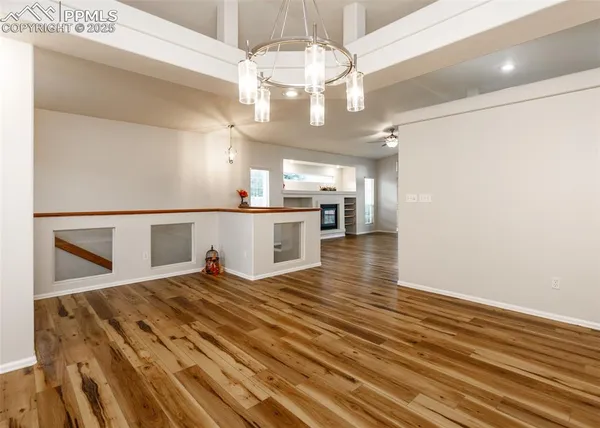 a view of a hallway with wooden floor and chandelier