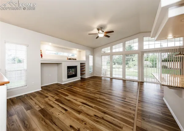 a view of empty room with wooden floor and fan