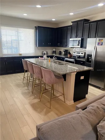 a kitchen with stainless steel appliances granite countertop a stove a sink a microwave a refrigerator and cabinets