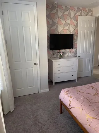 a bedroom with a flat screen tv on dresser and a white cabinet