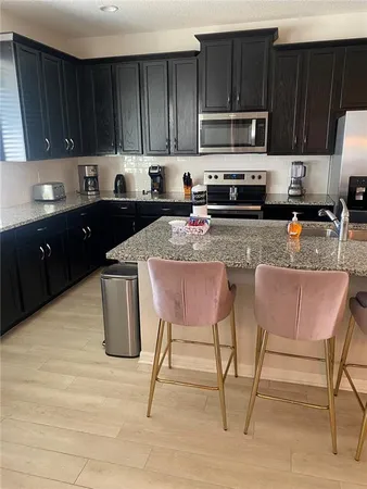 a kitchen with granite countertop wooden cabinets a stove top oven a sink and dishwasher