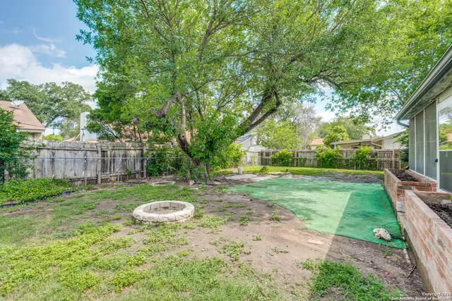 a view of a backyard with table and chairs and wooden fence