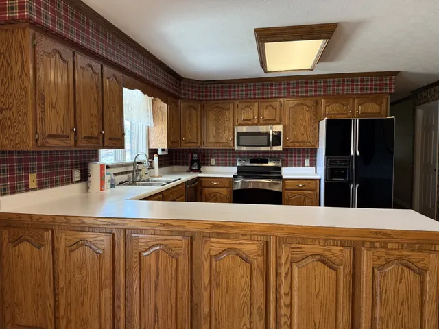 a kitchen with stainless steel appliances a sink cabinets and a window