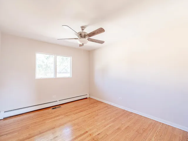 an empty room with a window and ceiling fan