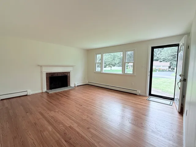 an empty room with wooden floor fireplace and windows