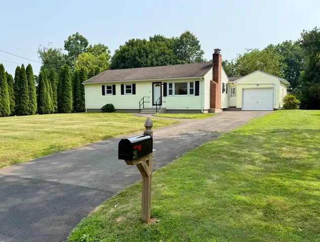 a front view of a house with a yard and trees