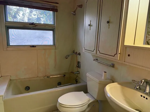 a bathroom with a sink a mirror a window and a bathtub