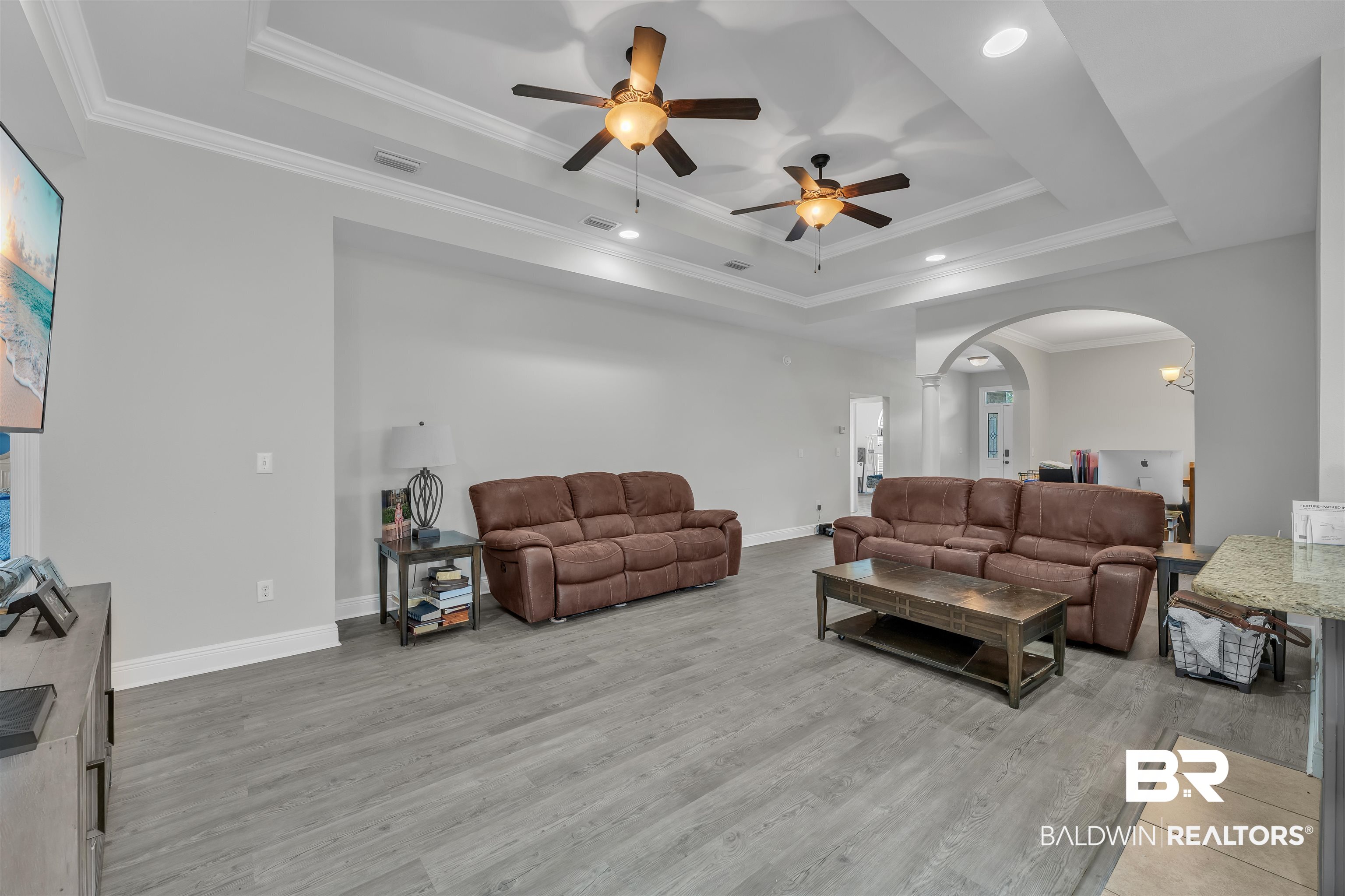 22565 Nana Loop East Silverhill, AL 36576 - Photo 6 of 26 Living area featuring light wood finished floors, crown molding, arched walkways, a ceiling fan, and a tray ceiling