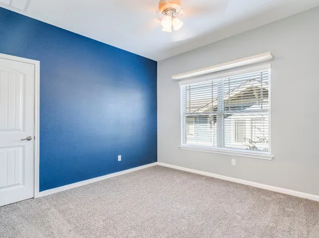 an empty room with chandelier fan and windows