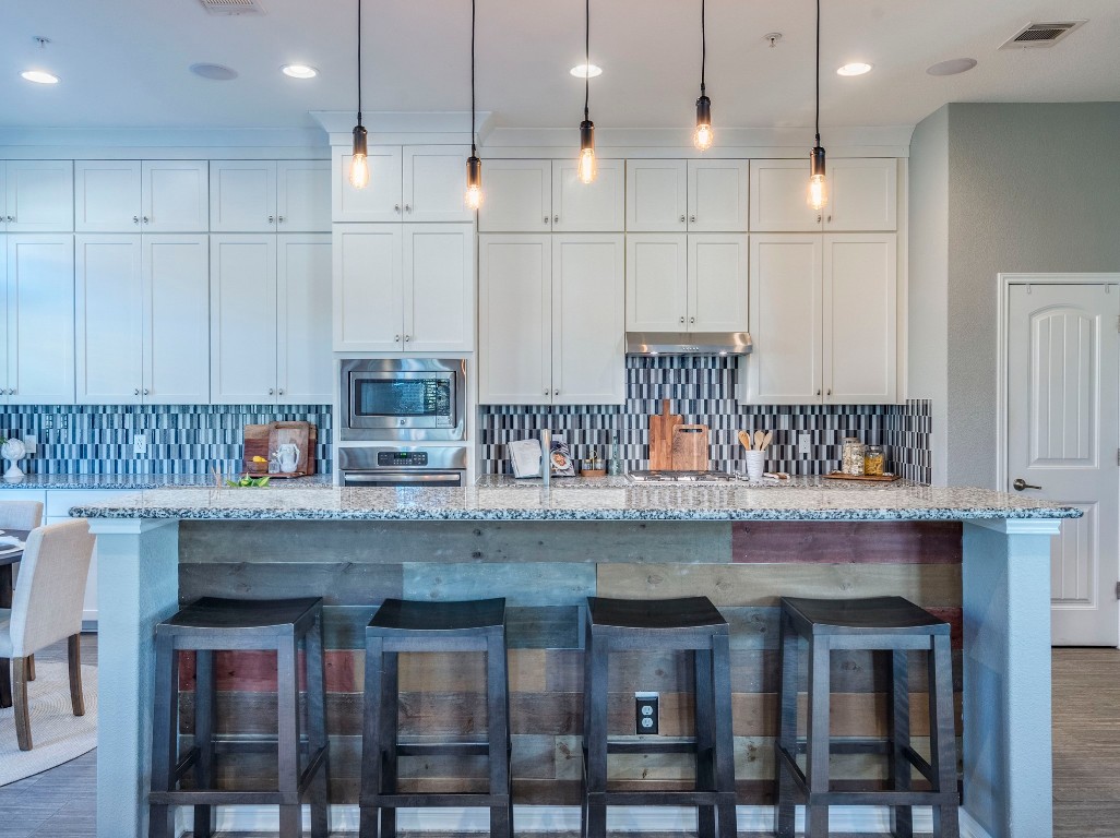 2930 Grand Oaks Loop, Unit 1903 Cedar Park, TX 78613 - Photo 7 of 36 a kitchen with stainless steel appliances granite countertop a table chairs sink and cabinets