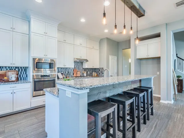 a kitchen with stainless steel appliances granite countertop a table chairs sink and cabinets