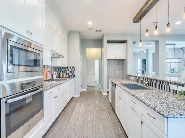 a kitchen with granite countertop a table chairs microwave and cabinets