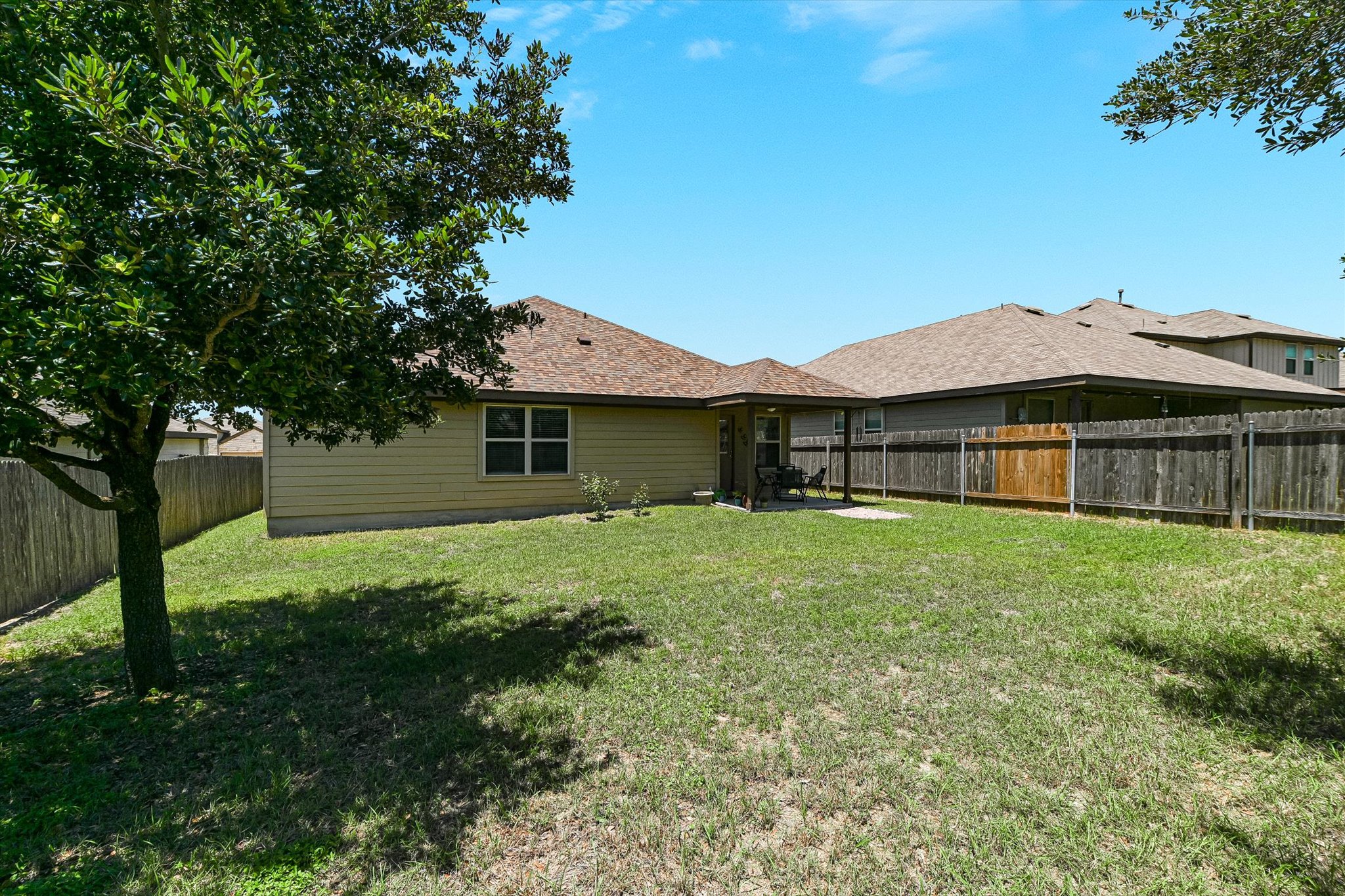 536 Dragon Ridge Road Buda, TX 78610 - Photo 20 of 20 Expansive backyard featuring a mature tree, manicured lawn, and privacy fencing