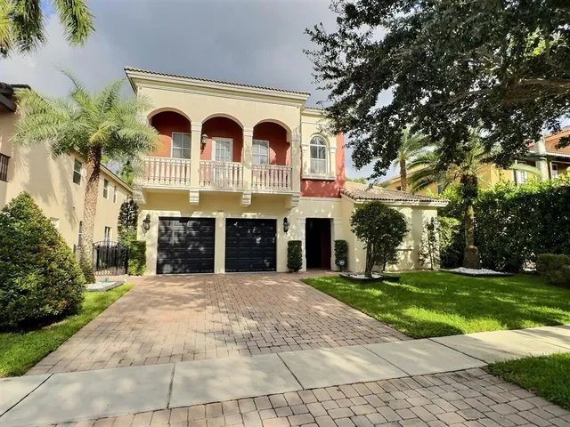 a view of a grey house with a big yard and large trees
