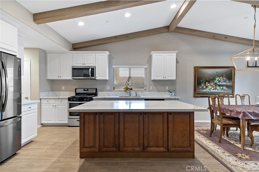 1189 Heritage Drive Calimesa, CA 92320 - Photo 5 of 36 a kitchen with stainless steel appliances a sink a stove a refrigerator cabinets and a center island