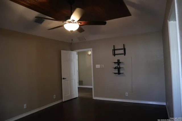 en empty room with wooden floor and fan