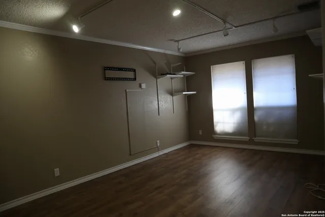 an empty room with wooden floor and windows with curtains
