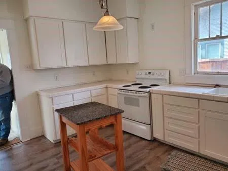 a kitchen with granite countertop white cabinets a sink dishwasher and a stove with wooden floor