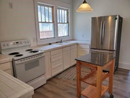 a kitchen with a refrigerator stove and wooden floor